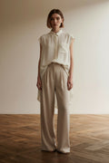 Full body view of the model wearing Theory 100% Zijden Mouwloze Blouse Crème – Luxe Silk Shirt met High-Low Zoom – Maat P
