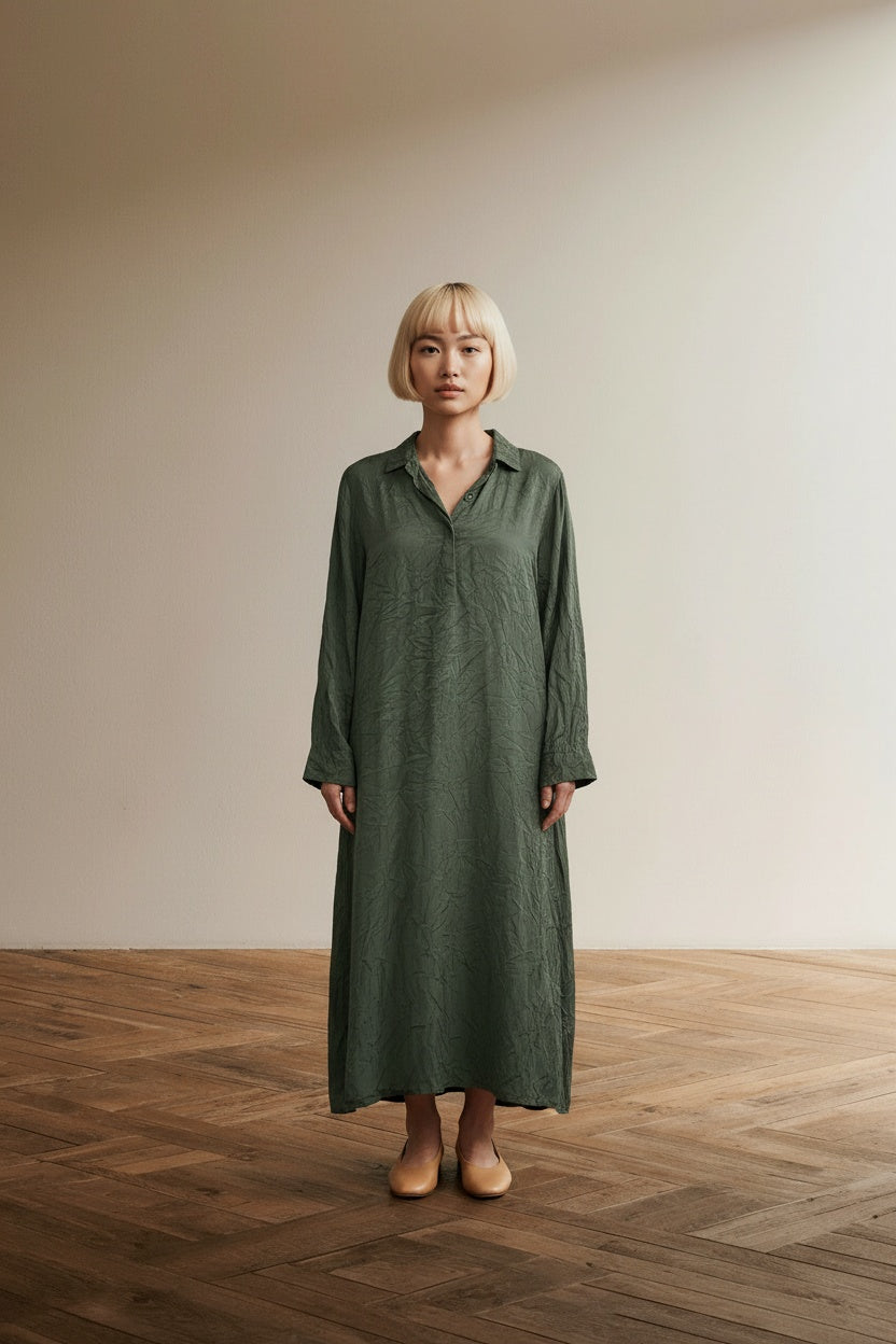 Full body view of the model wearing OSKA Crinkle Jurk Olijfgroen – Luchtige A-Lijn Jurk – Minimalistische Designerjurk